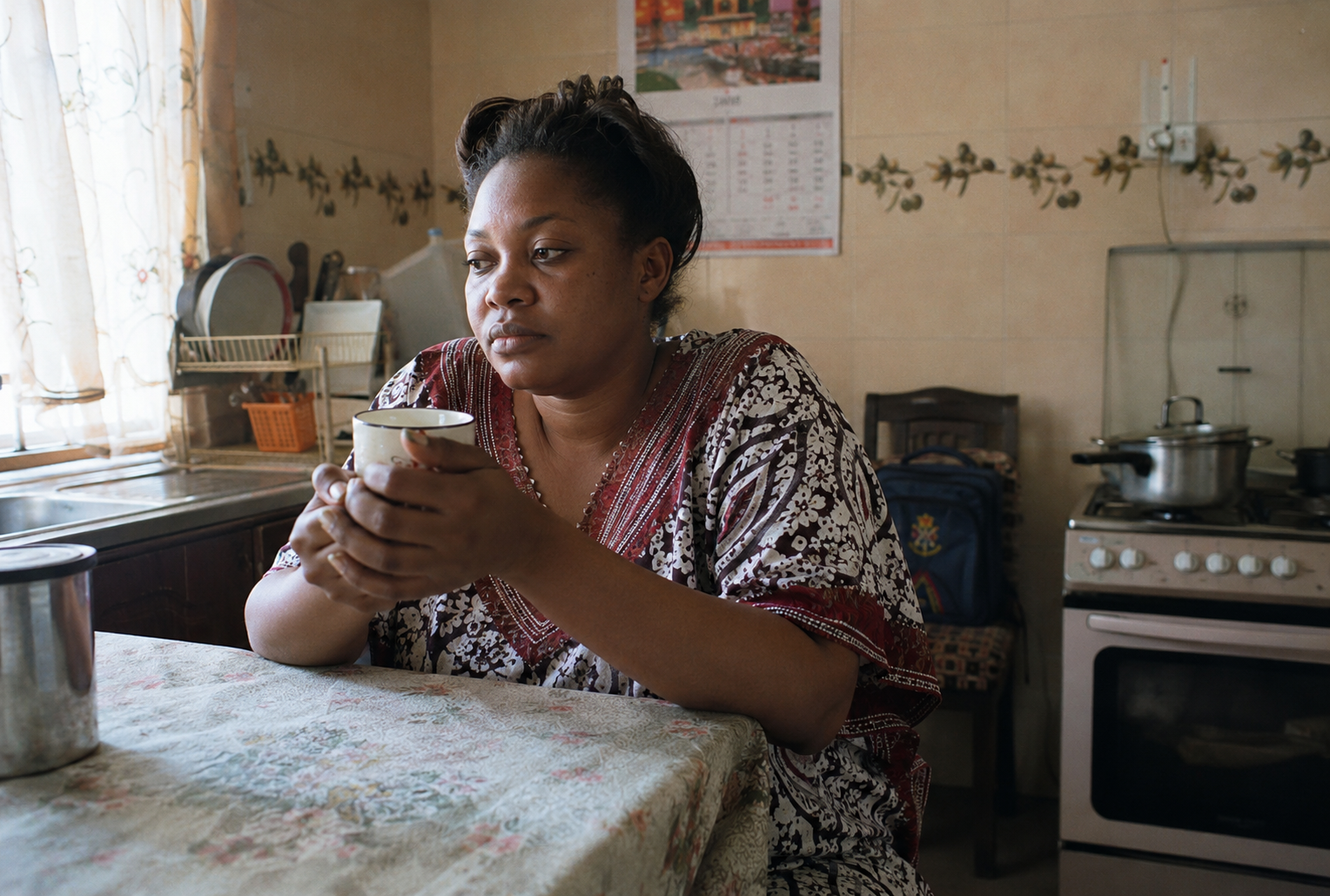 Nigerian mother sitting quietly at a kitchen table in the morning